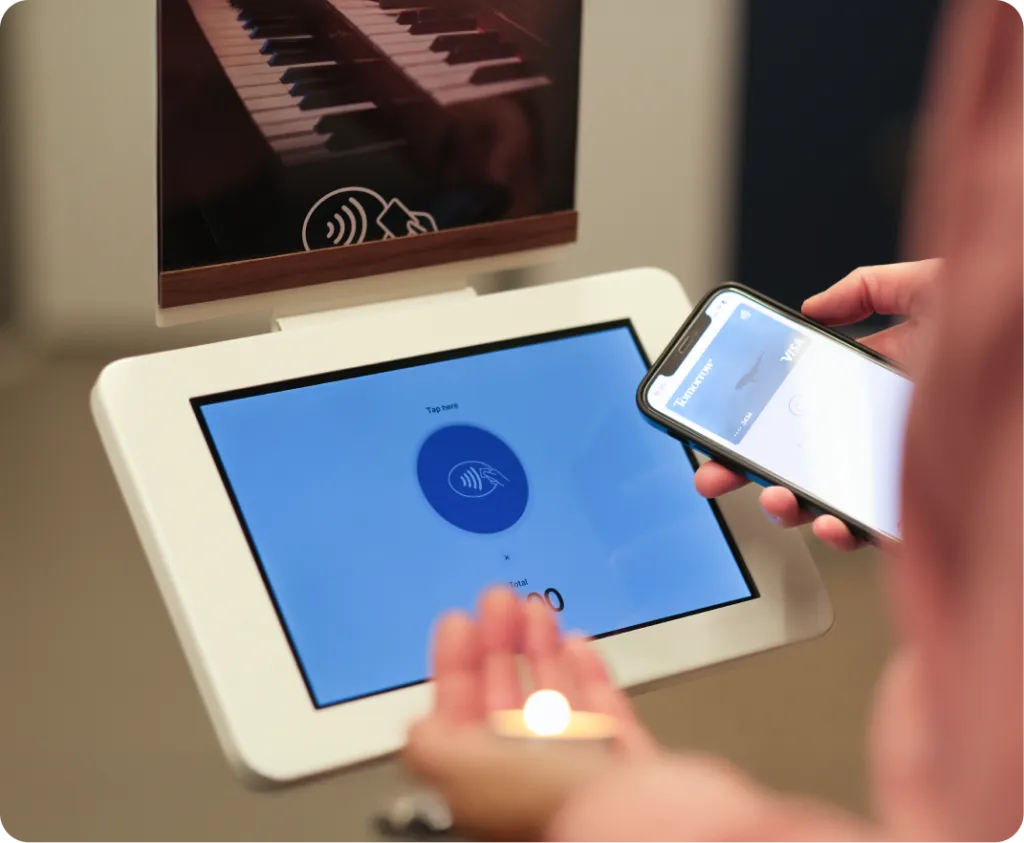 The ChurchDesk terminal as a stand with a candle poster while someone donates a candle using their smartphone