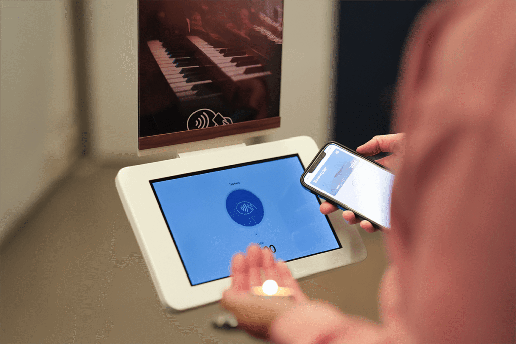 The ChurchDesk terminal as a stand where a person can donate contactlessly using their smartphone